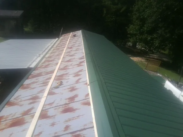 Old rusted panels beside newly installed green metal roofing — Wind Damage Roof Repair by Roofing Brothers in Berry Creek