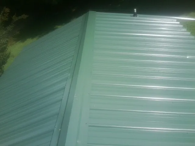 New green metal panels meeting at the ridge of a roof — Flat Roof Repair work by our crew in Berry Creek