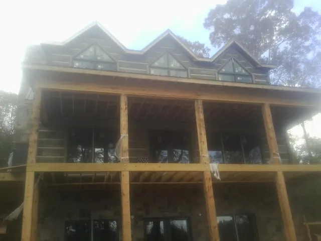 Dormers and porch framing on a large log home under construction — Roof Coating work by our crew in Berry Creek