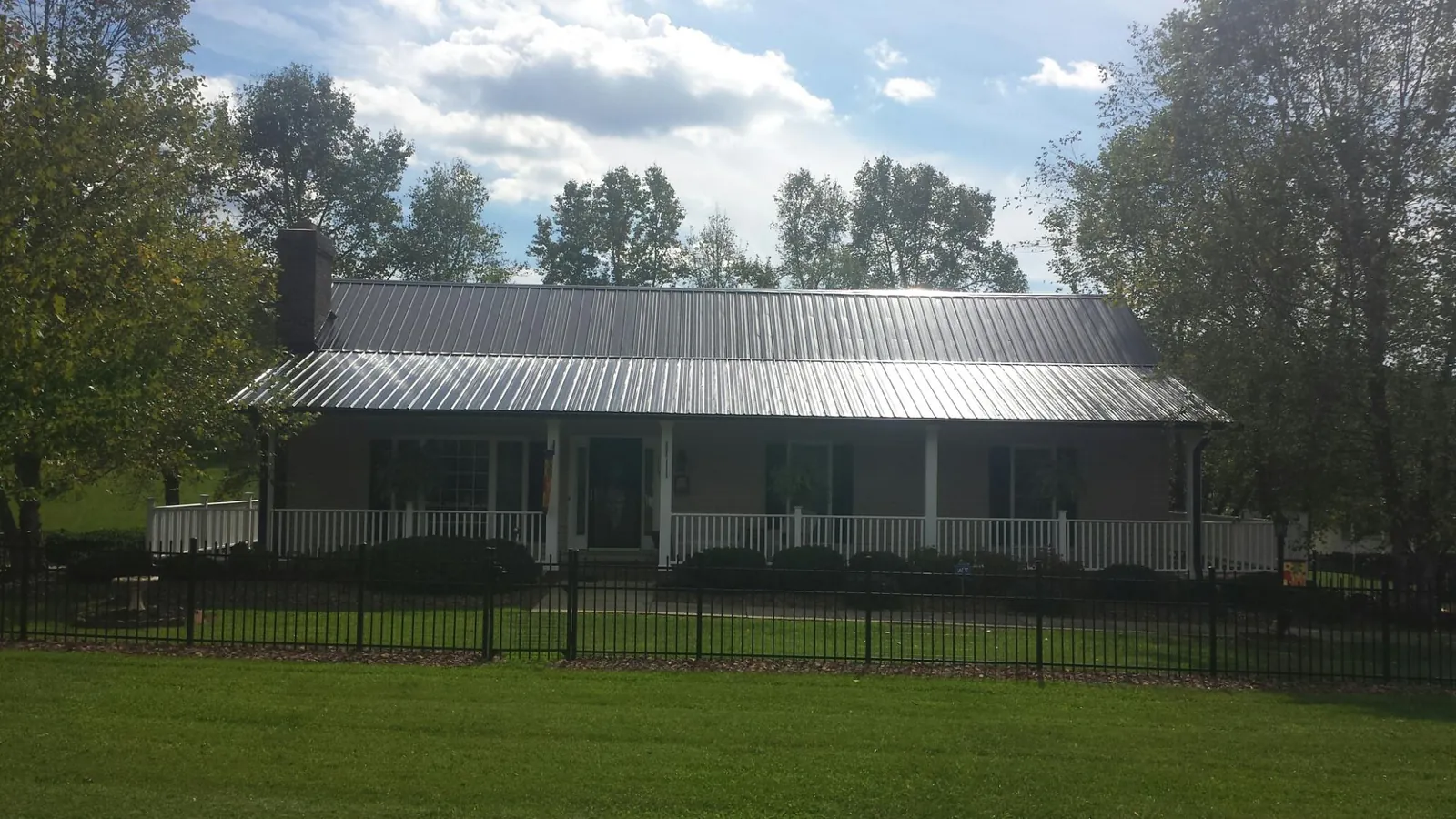 Gray metal roof on a brick ranch with a full width front porch — Gutter Guard Installation work by our crew in Berry Creek