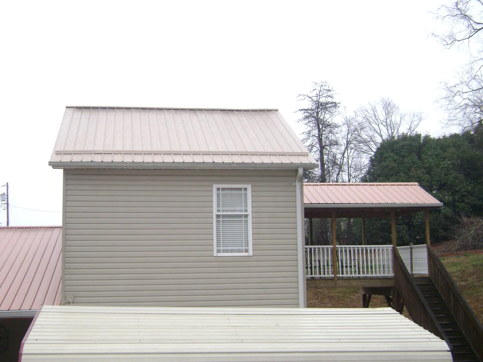 Tan metal roofs on a two story addition and attached porch, from a Roof Replacement job in Berry Creek