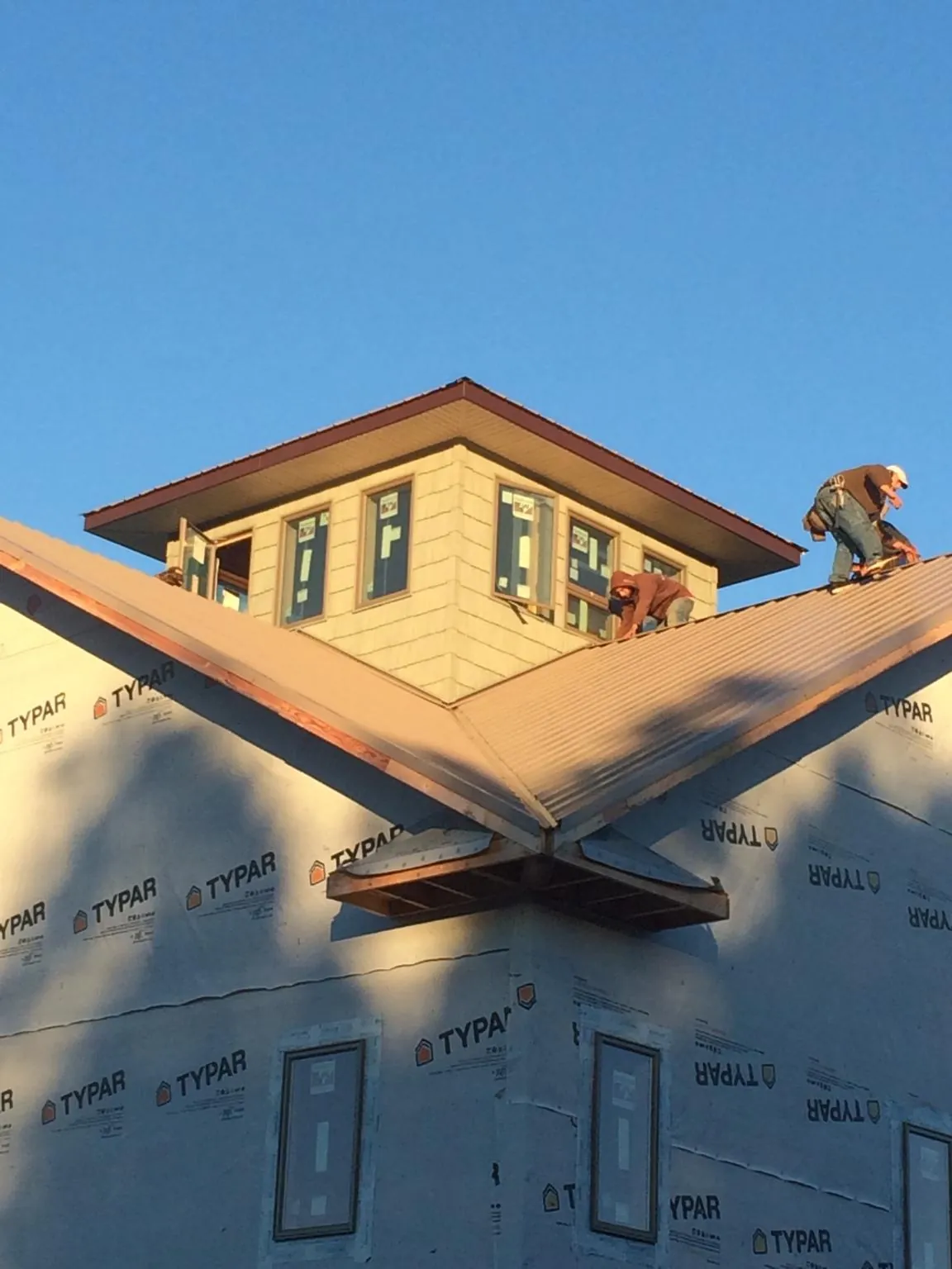 Roofers working around a rooftop cupola on a new metal roof at sunset — Roof Waterproofing in Berry Creek by Roofing Brothers
